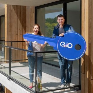 Huurder krijgt een grote symbolische sleutel van verhuurmakelaar om sleuteloverdracht te vieren