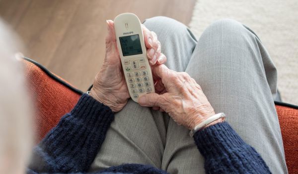 Oude dame met telefoon in handen op schoot