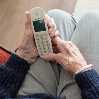 Oude dame met telefoon in handen op schoot