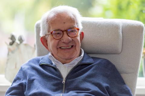 Oudere man lachend in stoel